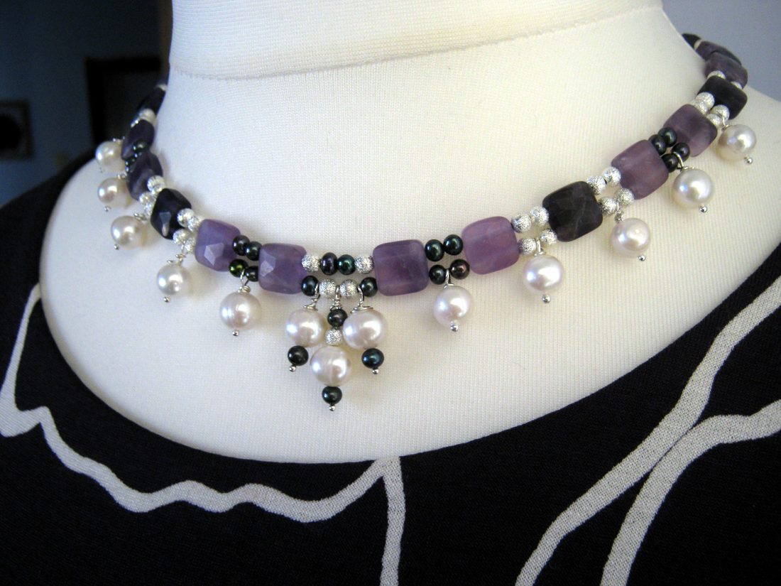 An amethyst and freshwater pearl choker displayed on a cream dress form.